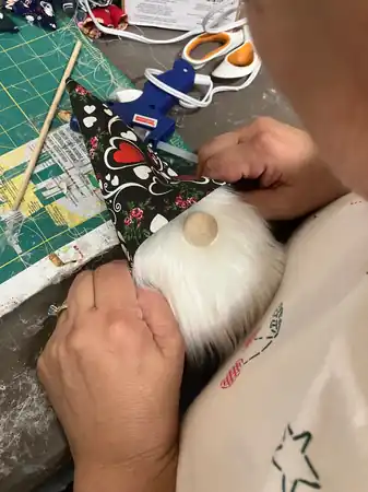 Cathy fitting a patterned fabric hat onto a handmade gnome